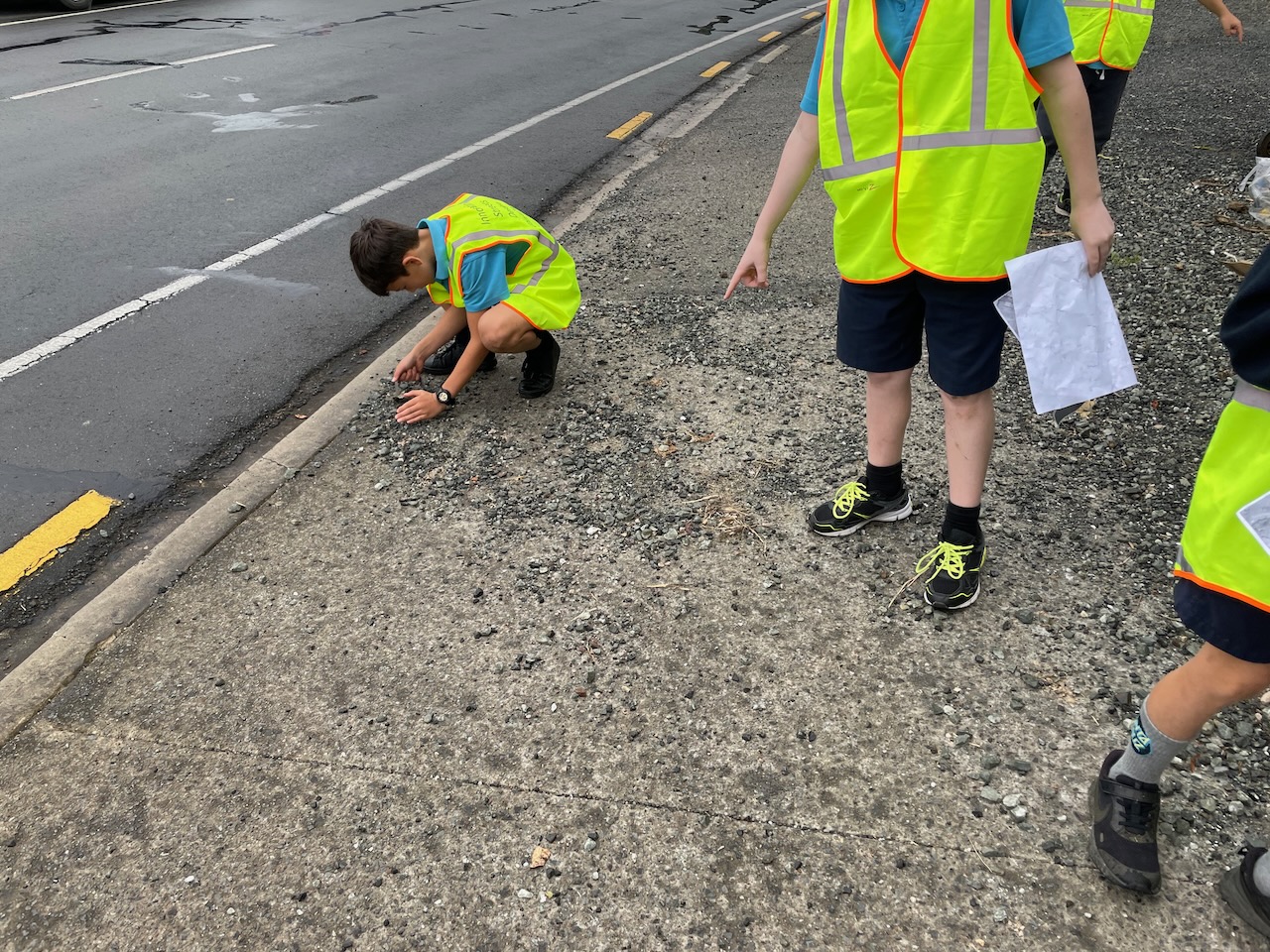 children on the side of the road looking at the footpath surface