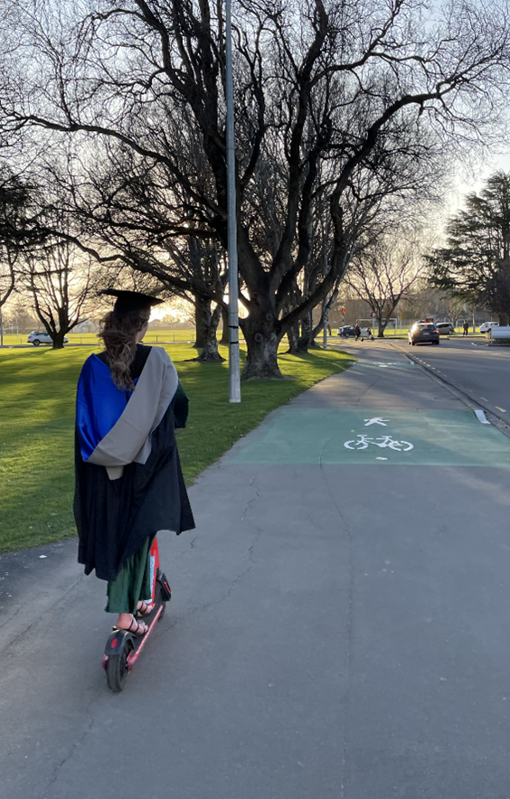 Luca riding away on a scooter in full ​​academic regalia