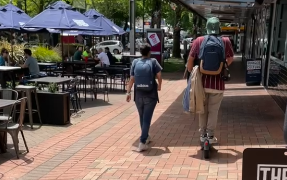 e-scooter rider beside a pedestrian on a footpath