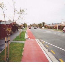 red cycling path next to road.