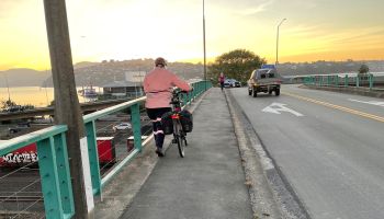 Cyclist walking their bike across a bridge in Dunedin